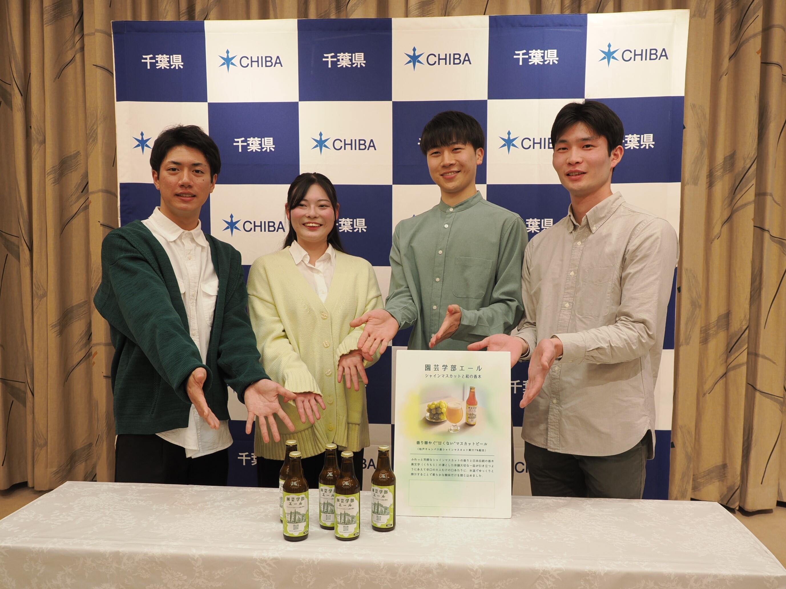 シャインマスカットビールの前で記念撮影をする学生